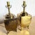 A striking pair of vintage Chinoiserie brass table lamps, richly engraved with serene landscapes, cranes, bamboo, and...