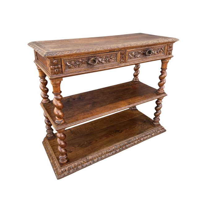 Antique carved oak console table featuring finely turned barley twist legs and rich floral carving to the apron. The piece...