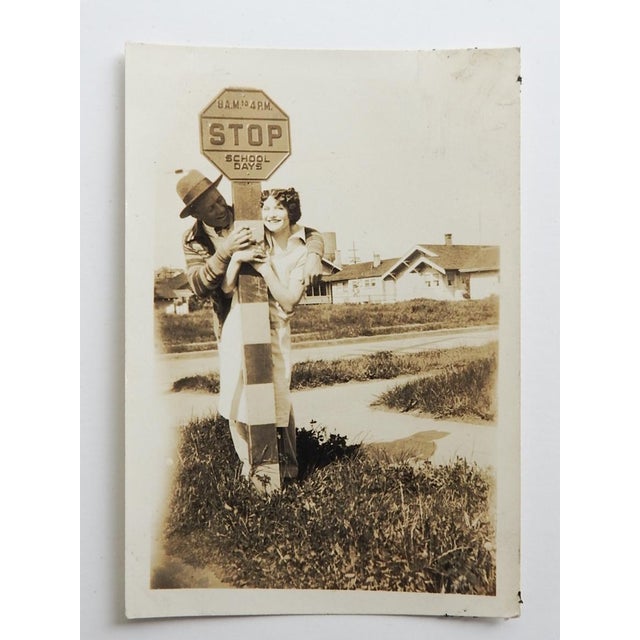 1920's sepia tone snapshot photograph of a young couple being silly at a school stop sign. Unframed, corner wear.