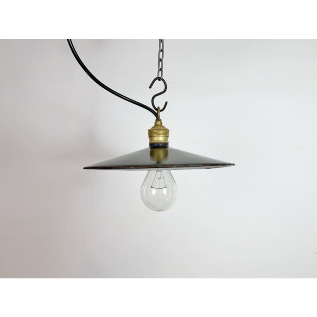 Vintage industrial enamel pendant lamp from the 1930s. It features a dark blue enamel shade with white enamel interior and...