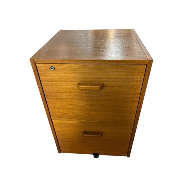 This product is a vintage Mid-Century Danish modern teak filing cabinet with a lock and caster base. The elegant brown...