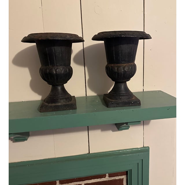 Classic, and heavy for their size, mid 20th century cast iron urns with very unusual scrollwork designs around the rims....