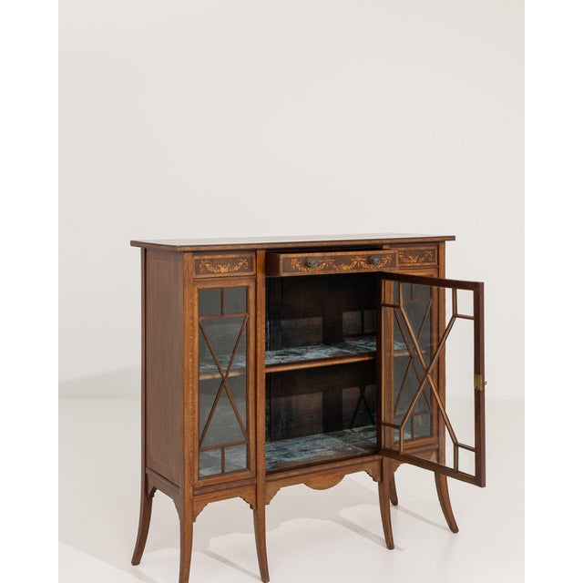 Here is a display cabinet, its dark mahogany with inlay, glass doors open the first thing to catch the eye. Originating in...
