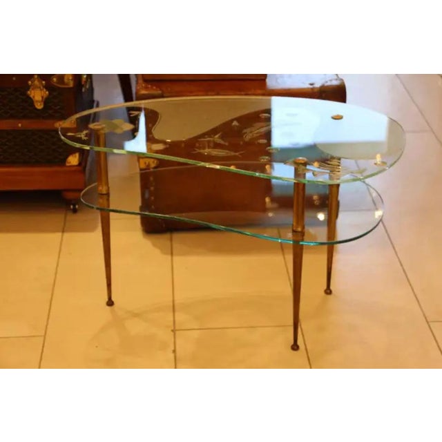 This very nice mid century glass top side table or coffee table features a free style shape and rests on 3 brass legs. It...