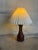 A turned sculptural teak base pairs with a pleated beige shade for an organic silhouette. Soft diffused light enhances its...