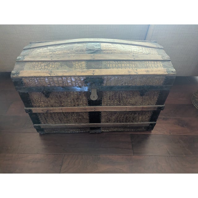 Wooden chest covered with leather. Leather handles on both sides. Dark metal banding, ornate hardware, and wooden slats...