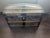 Wooden chest covered with leather. Leather handles on both sides. Dark metal banding, ornate hardware, and wooden slats...