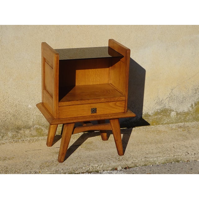 Attractive bedside table in light oak and veneer, with splayed legs. Quality craftsmanship, 1960s. Black lacquered glass...