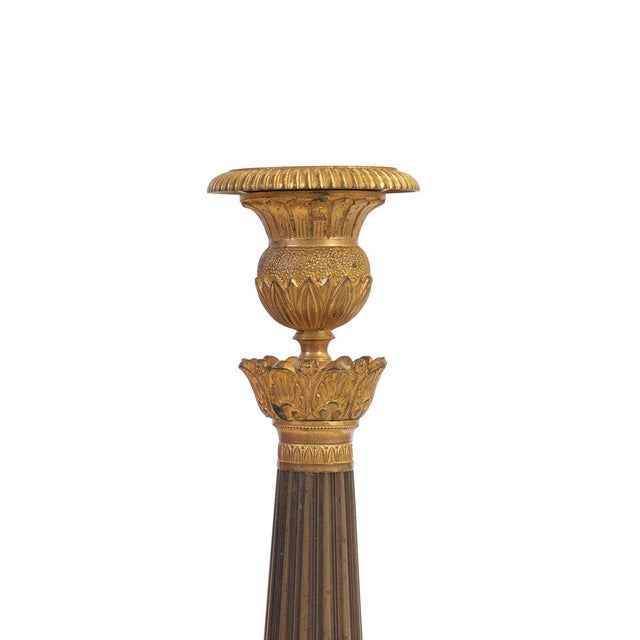 Pair of candlesticks, Empire style, France, circa 1810, gilt and patinated bronze, round base, fluted stem, patina...