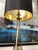 Elegant vintage table lamp featuring a tall, tapered form in smoky amber glass, anchored by a brass base and accented with...