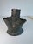 A metal vase with green patina. There are three openings for flowers and a place for a candle.