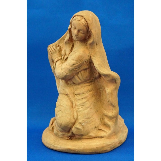 A terracotta sculpture, entirely hand-molded, depicting the Madonna with a veil kneeling in the classic nativity scene...