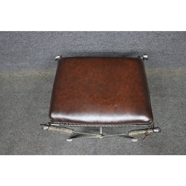 Handcrafted by Maitland-Smith, this distinctive X-base stool features a patinated iron frame with cast eagle head finials,...