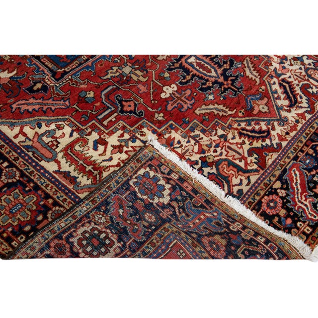Beautiful antique Heriz hand-knotted wool rug with a red field. This Heriz rug has a dark blue frame and multi-color...