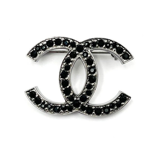 This is part of Chairish’s Costume Jewelry assortment. Chanel Silver CC Black Crystal Medium Brooch * Marked 12 * Made in...