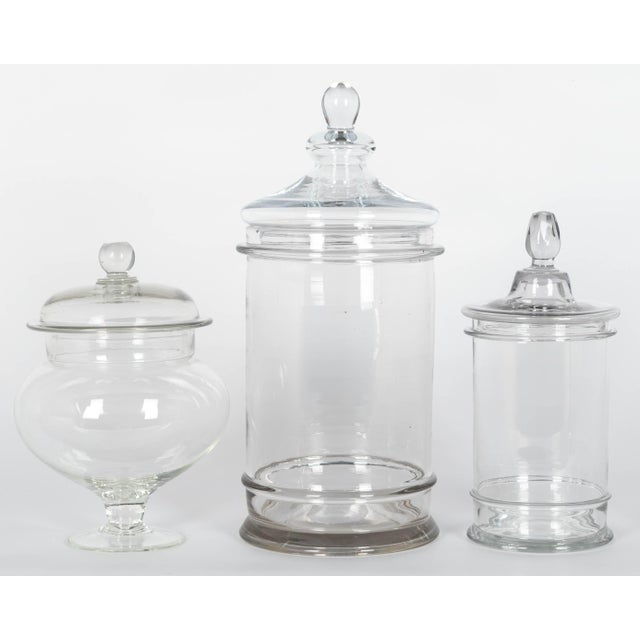 A set of three French hand-blown glass lidded apothecary or candy jars. Smooth form with knob on lid, each slightly...