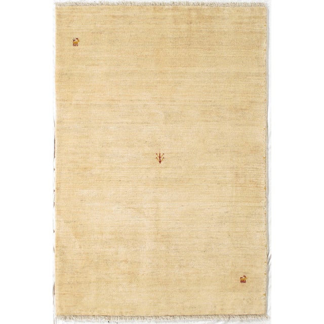 Vintage Persian hand-knotted Lori Gabbeh wool rug featuring a soft ivory field with sparse, delicately placed tribal...