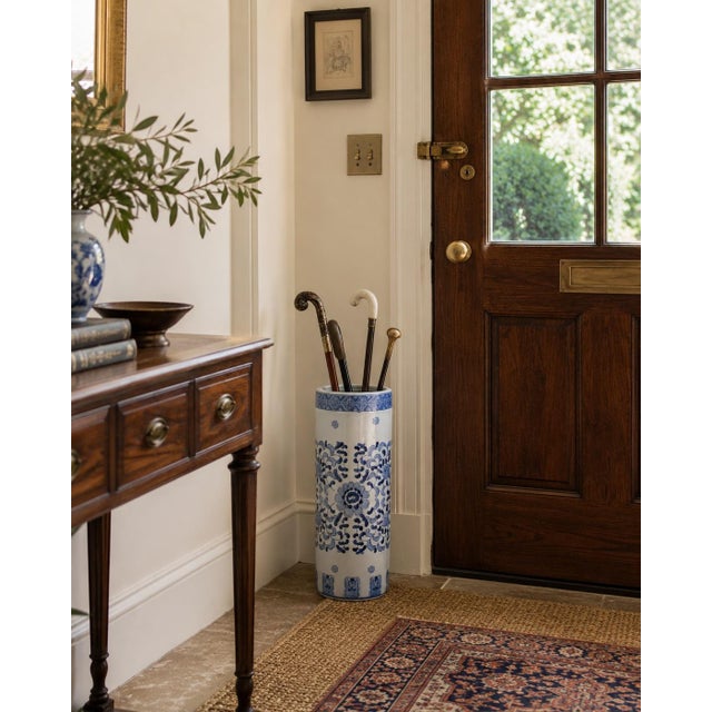 A classic late 20th-century blue and white porcelain umbrella stand, decorated in the Chinoiserie tradition with stylized...