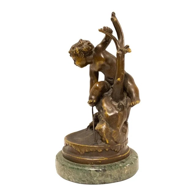 Sculpture of a boy playing, made of solid hand-carved bronze with a black patina and a circular green marble base. France,...