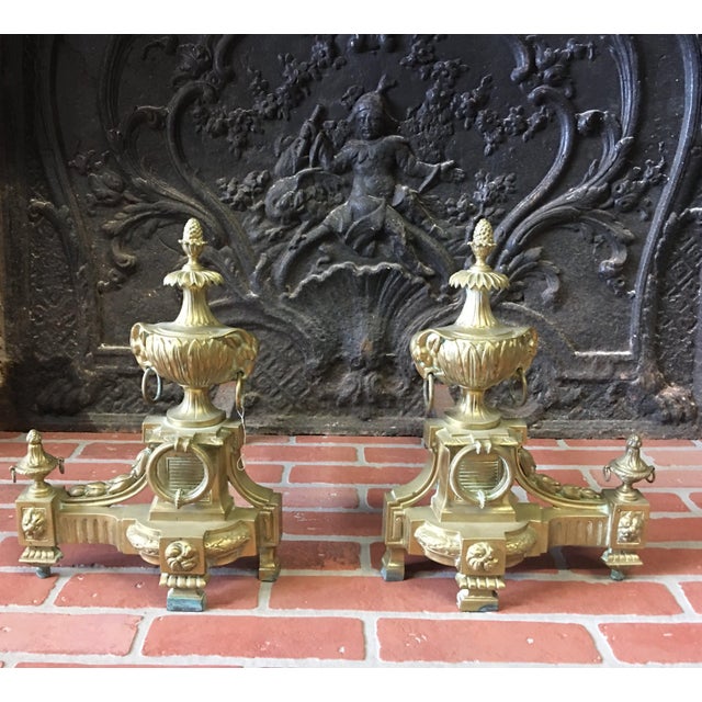 A pair of fine quality French bronze chenets in the Louis XVI style with small pineapple finials on stylised palm trees...