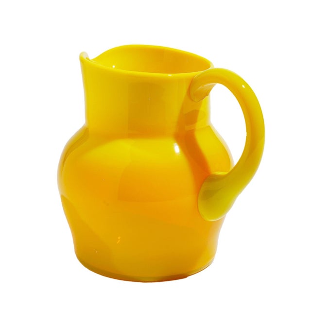 A beautifully proportioned Cadmium yellow opaline blown art glass pitcher. The pitcher has a bulbous body with an...