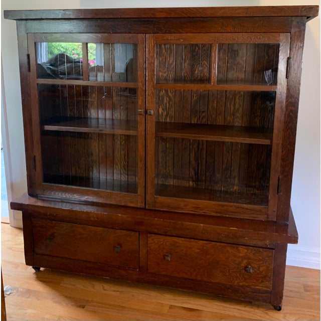 Antique Craftsman Cabinet with glass doors and two drawers below. Stained in a walnut finish with wood knobs.