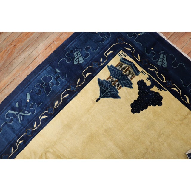An early 20th century Chinese Peking rug with a spacious open field design on a creamy yellow field and pretty blue...