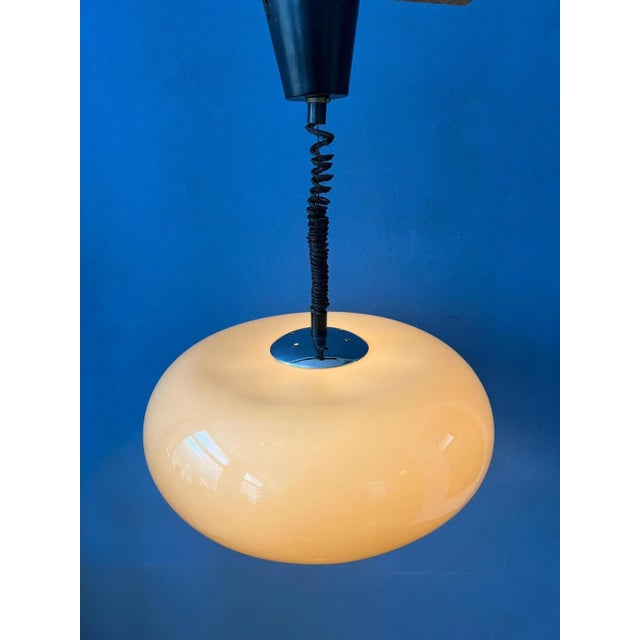 UFO-like acrylic glass space age pendant lamp in beige coffee colour. The acrylic glass shade produces a warm glow. The...