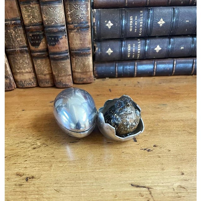 An antique cold painted inkwell featuring a small bird in a silver metal eggshell. The shell with cracked design is...