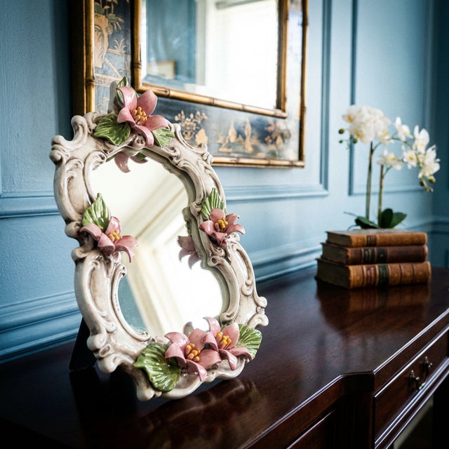 Vintage Capodimonte porcelain vanity mirror made in Italy, featuring an ornate rococo-style frame with applied pink...