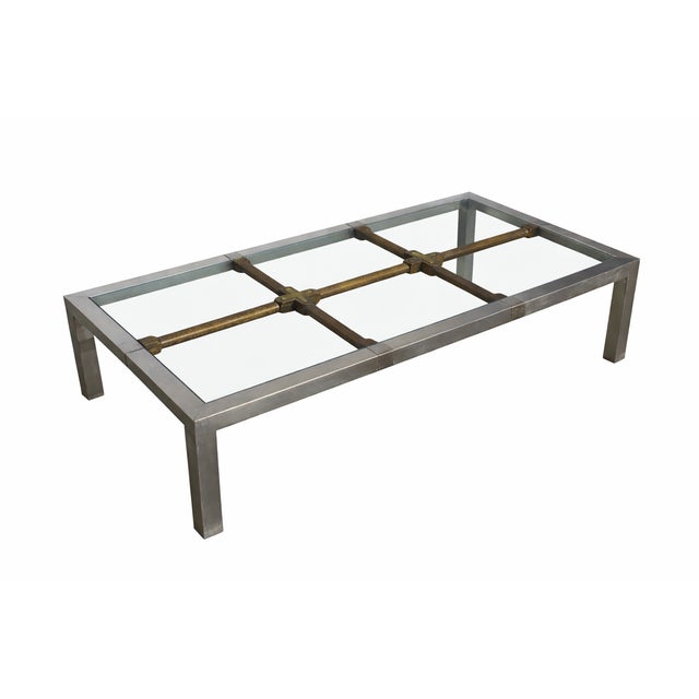 This Mid-Century Hollywood Regency Brushed Metal Coffee Table with Brass Accents, Glass Top, and Exposed Wood Grid Base is...