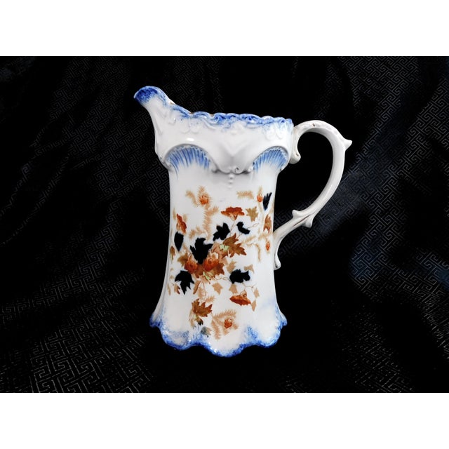 This is a Burslem marked pitcher in white with a blue, gold and pink leaf design and a blue trim. The porcelain is very...