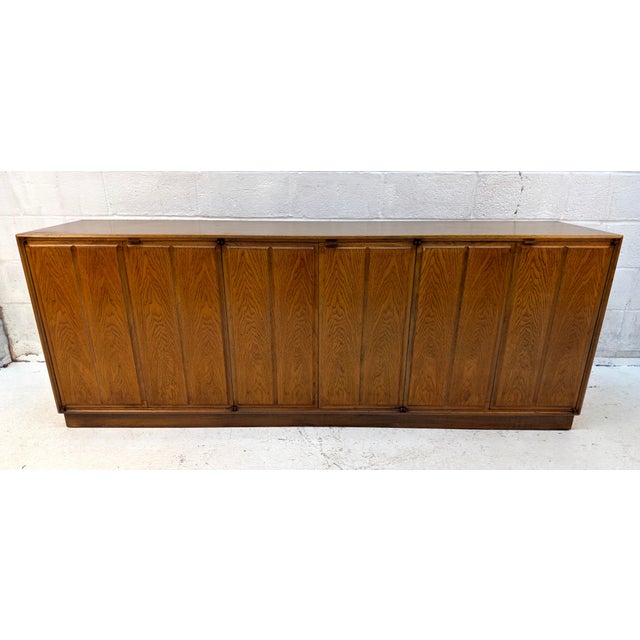 A timeless Mid-Century Modern walnut credenza featuring clean lines, warm wood tones, and understated vintage appeal. The...