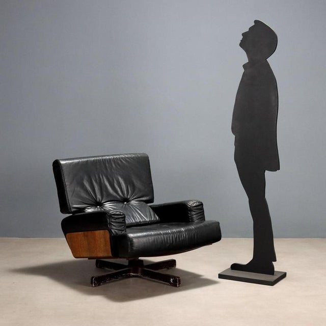 Vintage armchair with curved plywood frame with exotic wood veneer and black leather upholstery, metal legs. This piece is...