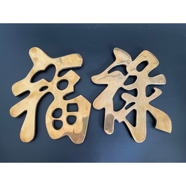A vintage set of brass trivets in the form of the Chinese Good Fortune and Prosperity symbols. Each trivet is fitted with...