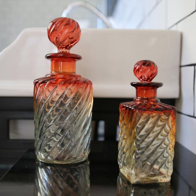 2 baccarat crystal bottles with twisted “bambou tors” decoration and red-pink color gradient. a large round, a small...