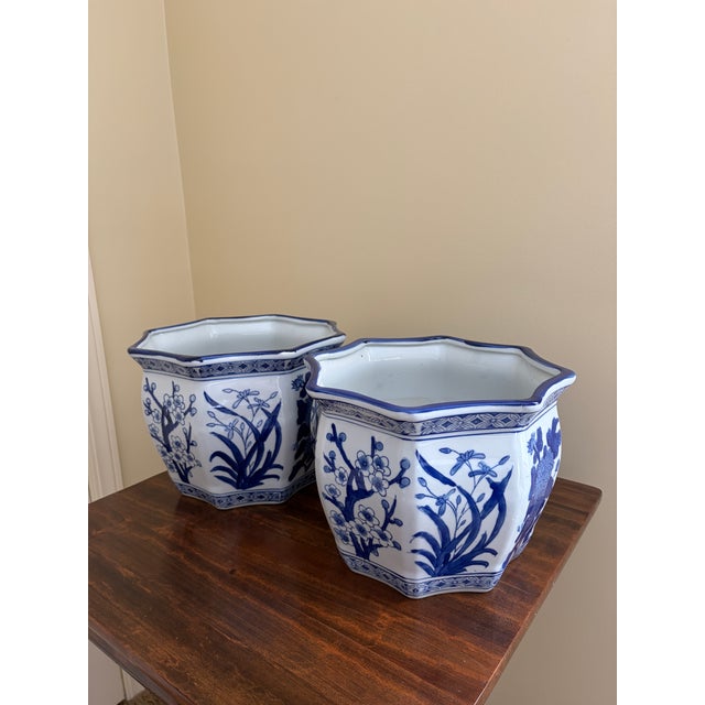 A classic pairing of blue and white porcelain planters, rendered in a softly faceted, scalloped form that feels both...