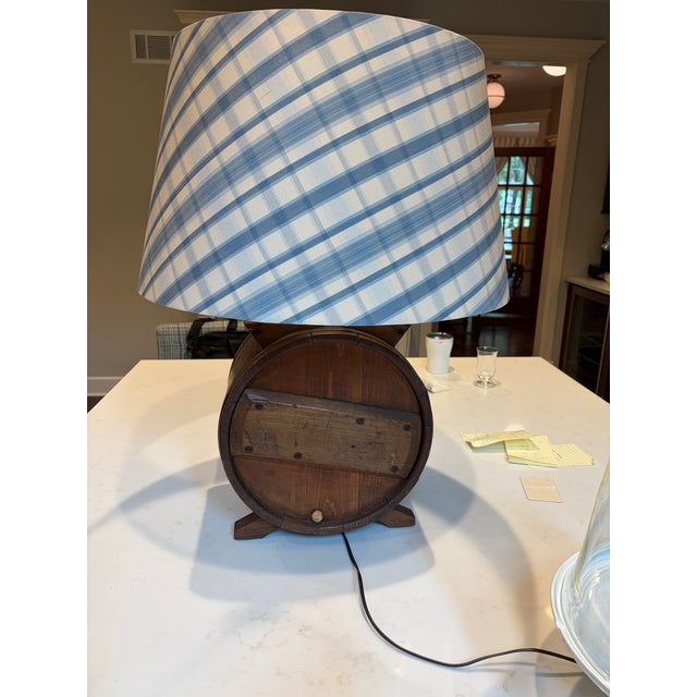 In the style of Anthony Baratta A custom lamp made from an antique butter churn with a custom lampshade of blue silk plaid...