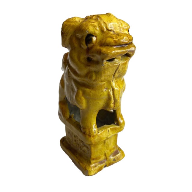 A pair of Chinese ceramic foo dogs joss stick holders on pedestals in an imperial yellow glaze.