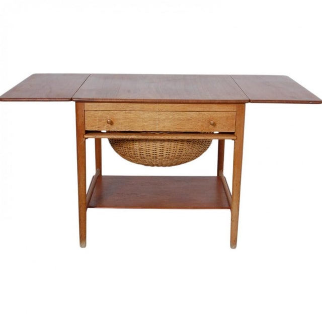 Sewing table with a table top of teak and frame of oak. The table is from the 1960s and appears in good condition but with...
