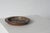 A low, wide bowl with a round, shallow shape, made of stoneware and covered with a multi-layered glaze in shades of brown,...