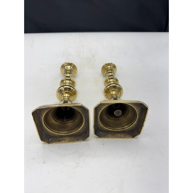 Pair of vintage Brass candlesticks featuring a turned design with square bases. Condition shows wear, including some...