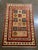 Hand-knotted Persian Kashkoli wool rug featuring a red field with a central grid of square panels, each containing...
