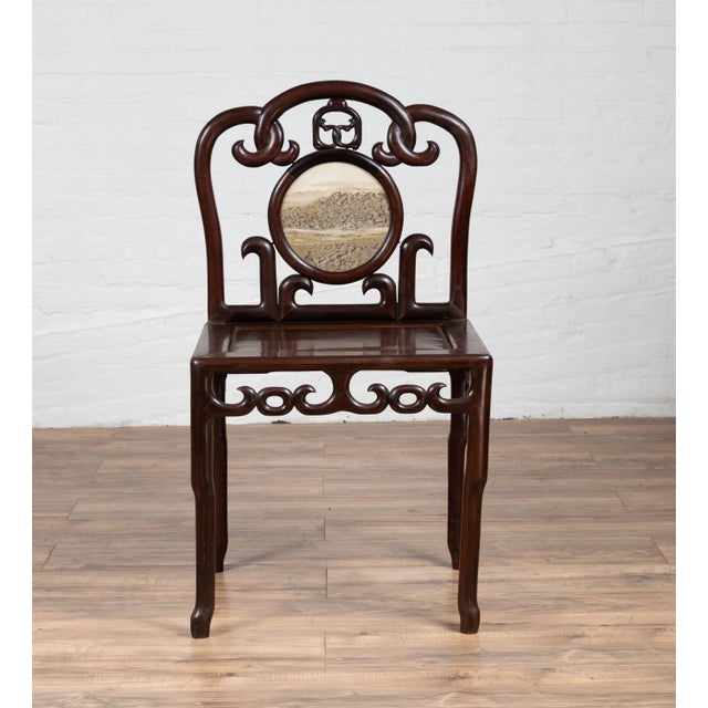 An antique Chinese rosewood side chair from the early 20th century, with marble medallion inlay and open fretwork. Born in...