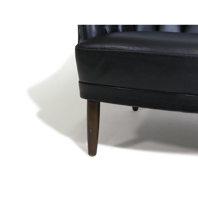 Danish loveseat settee with a double rounded back upholstered in the original black leather with classic button-tufted...