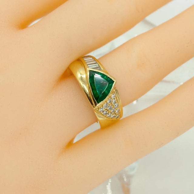 Crafted in rich 18K yellow gold, this bold ring showcases a striking trillion-cut emerald weighing approximately 2.00...