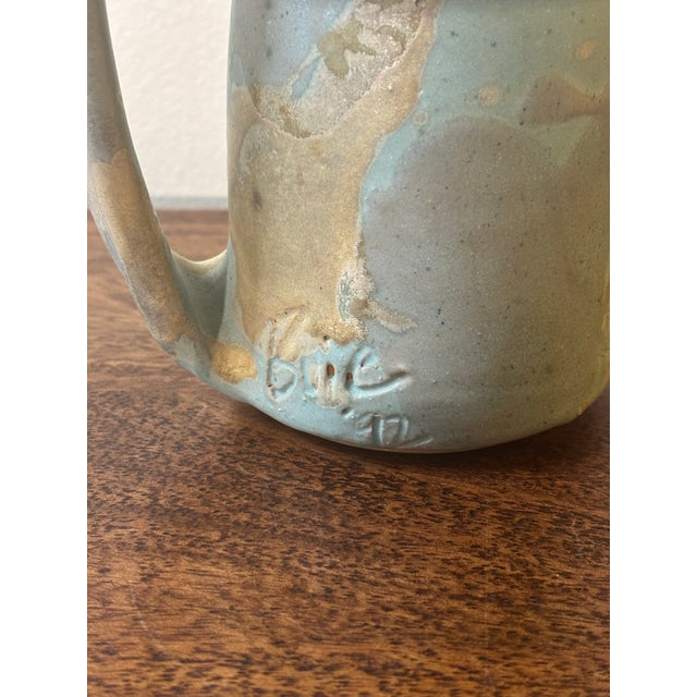 A sculptural postmodern studio ceramic vessel with a soft, atmospheric palette. Finished in a pastel blue glaze layered...