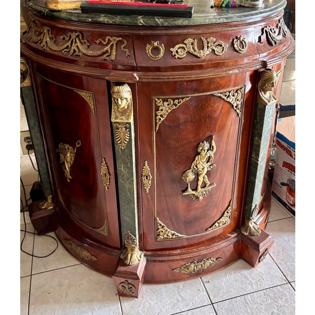 Elegant and highly decorative French Empire style demilune bar cabinet featuring a stunning green marble top and richly...