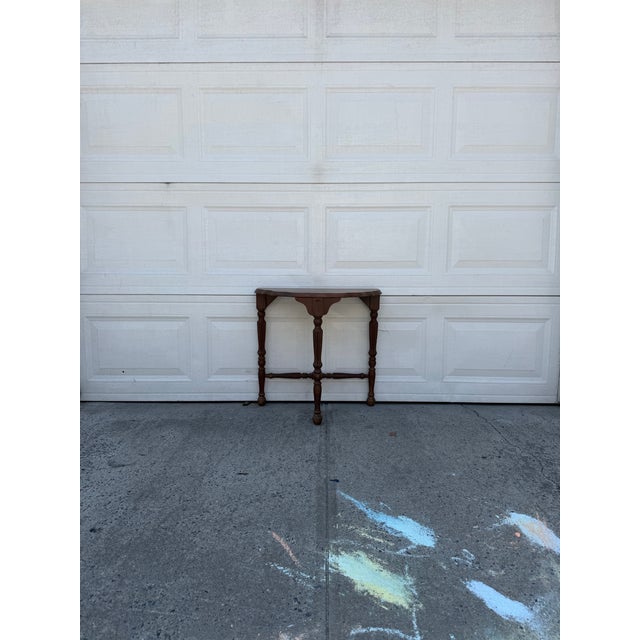 We have a vintage demilune console table for sale, featuring a classic half moon shape, warm wood finish, turned and...