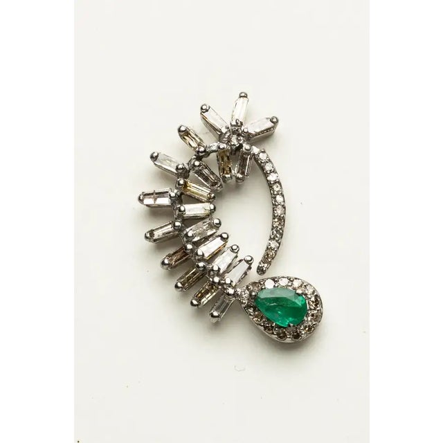 A very unusual pair of drop earrings that attach like a stud earring. A pear-shaped Zambian emerald surrounded by round,...
